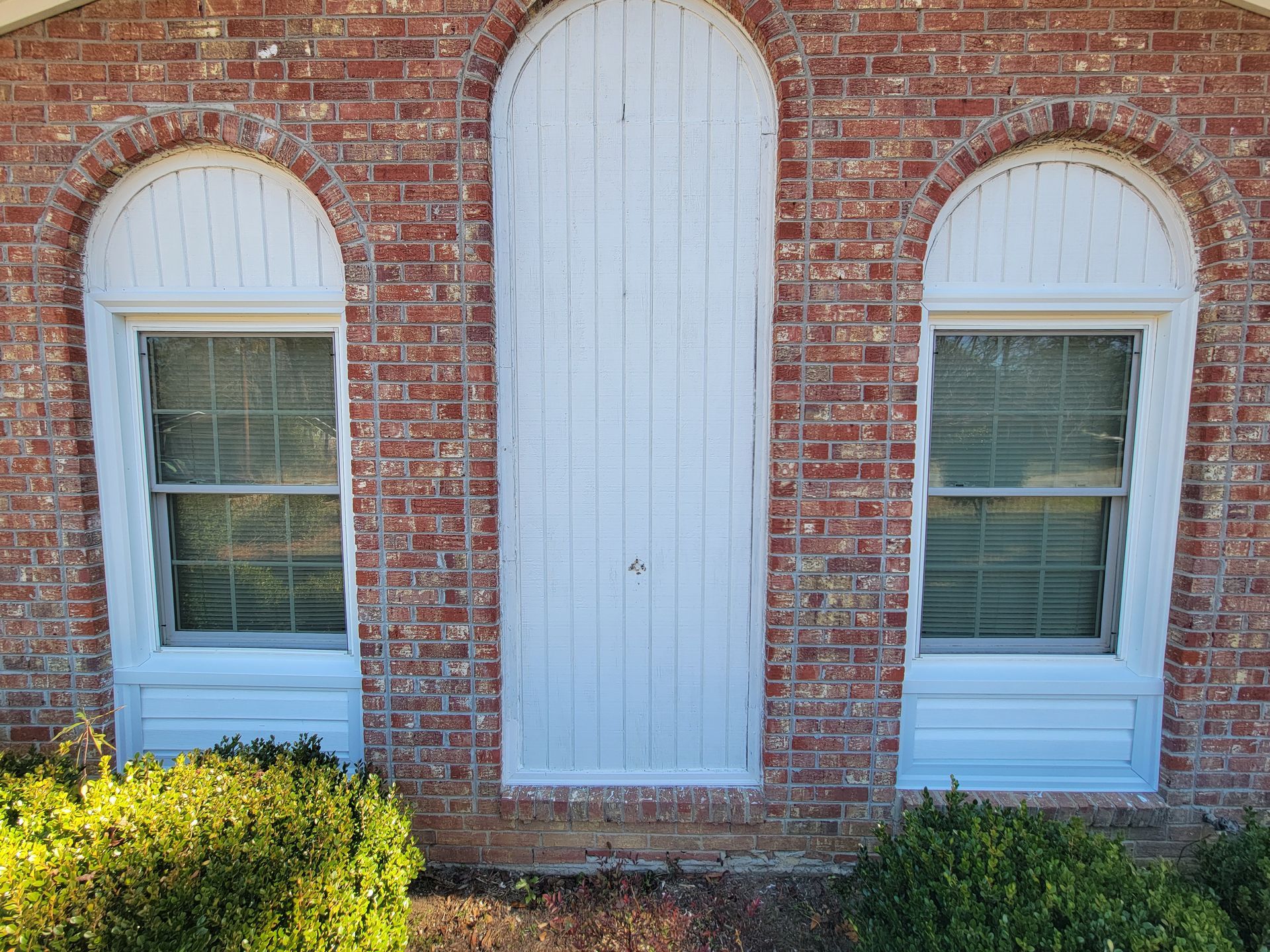 A brick building with arched windows and white shutters