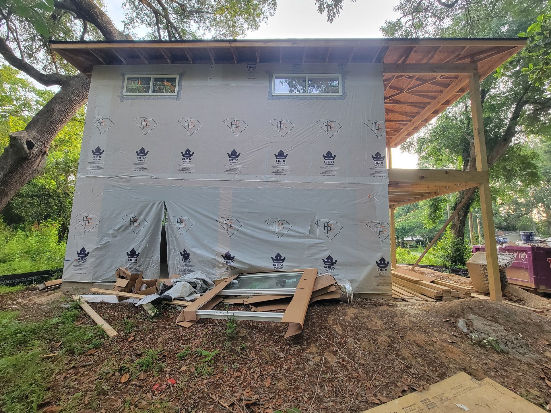 A house is being built in the woods and is covered in a tarp.