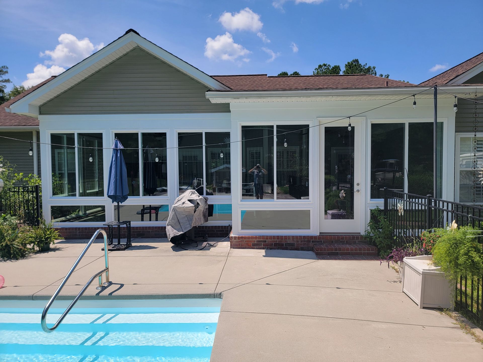 A house with a screened in porch and a swimming pool in front of it.