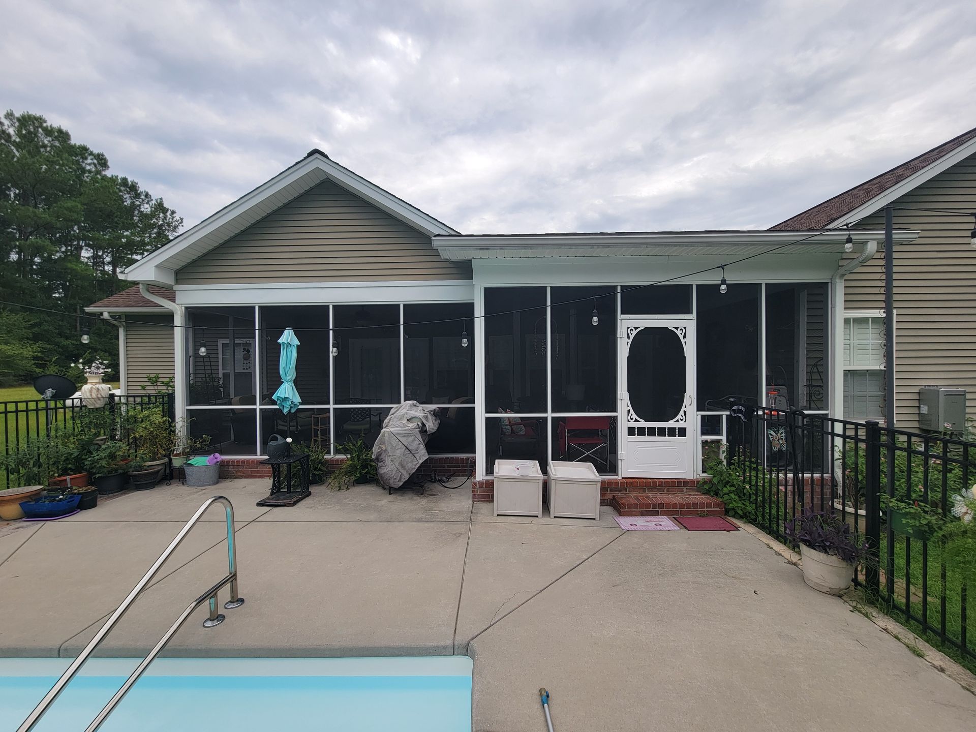 The back of a house with a screened in porch and a pool.