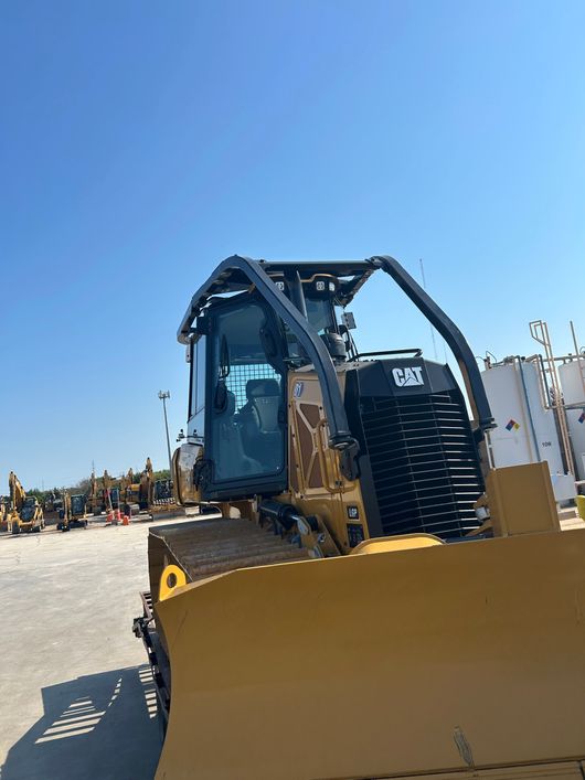 Small LGP Dozer in a dirt lot with construction equipment in the background under a blue sky.