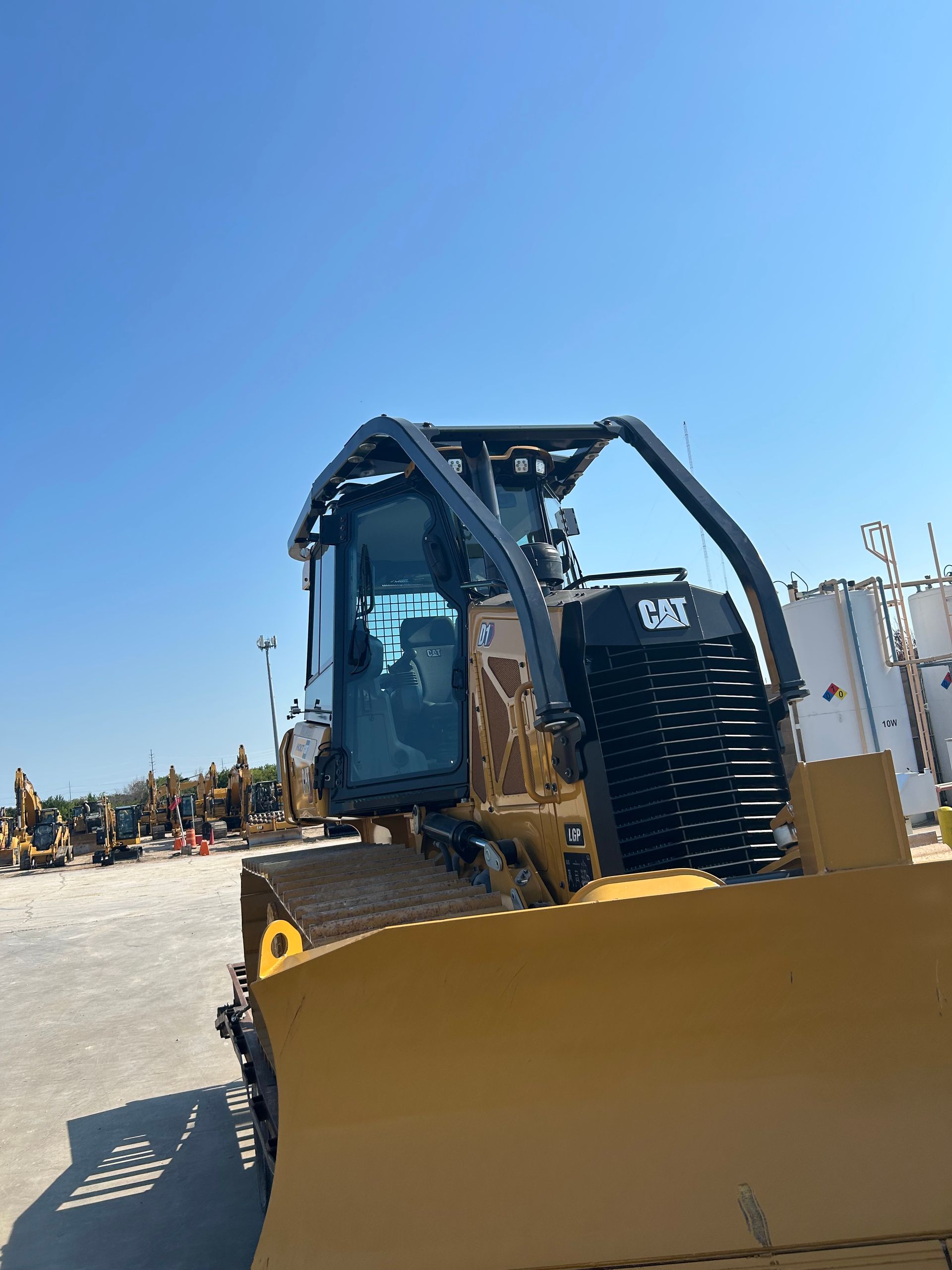 Yellow Caterpillar bulldozer against a clear blue sky.