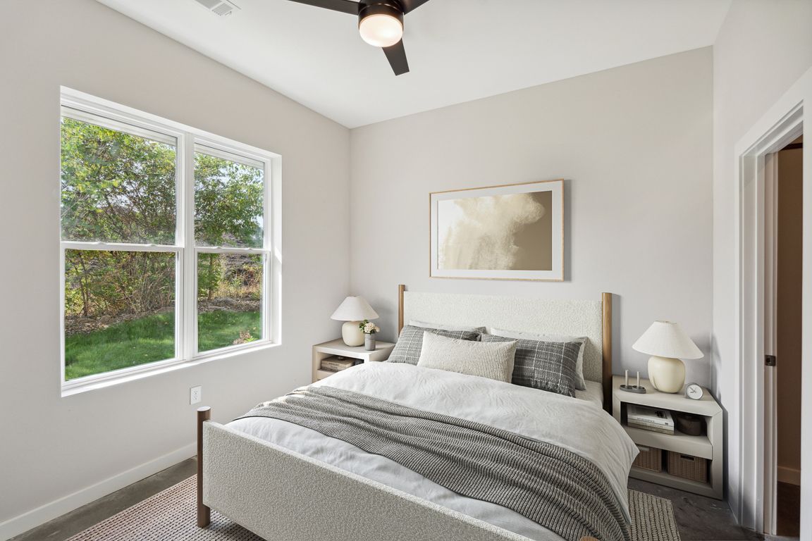 Bedroom with a bed, nightstands, window, and artwork. Light gray walls, neutral bedding.