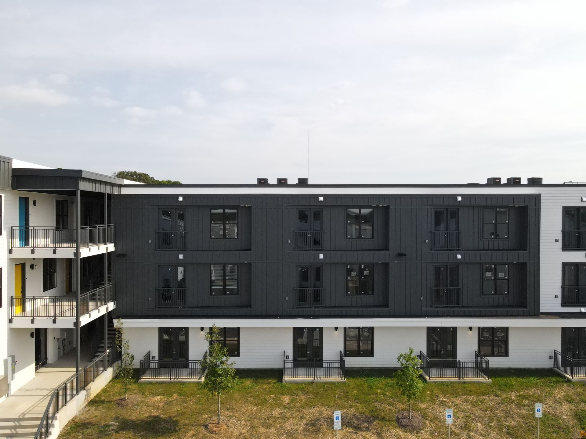 Exterior view of a modern multi-story building with dark and white panels, multiple windows, and balconies.