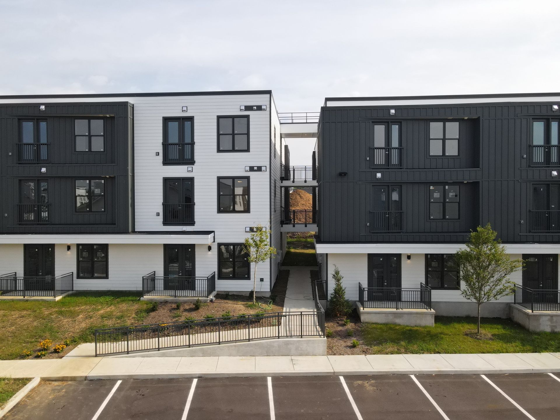 Modern apartment buildings with black and white facades and a walkway.