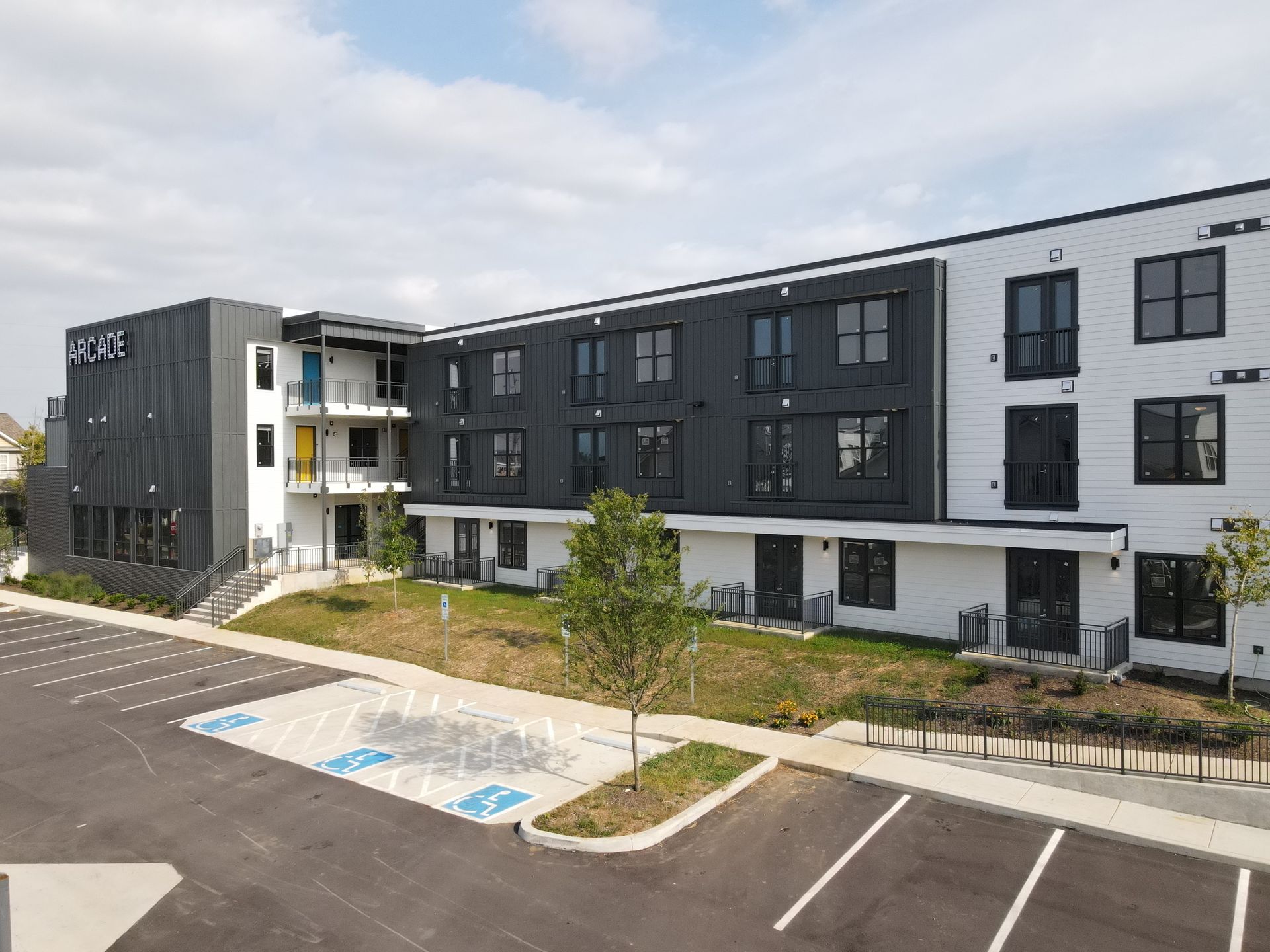 Modern building with black and white facade, blue accents, and accessible parking spaces.