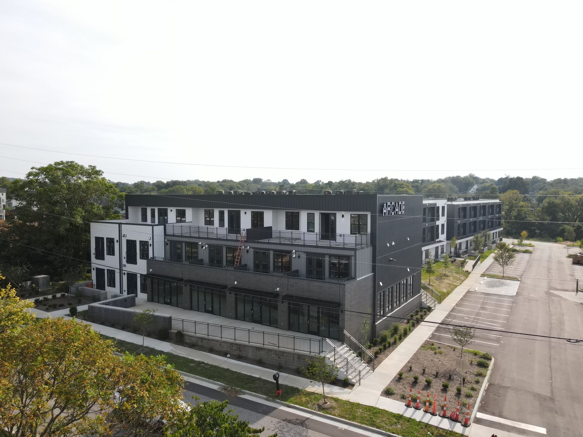 Modern multi-story apartment building with dark and light gray exterior, landscaped lot.