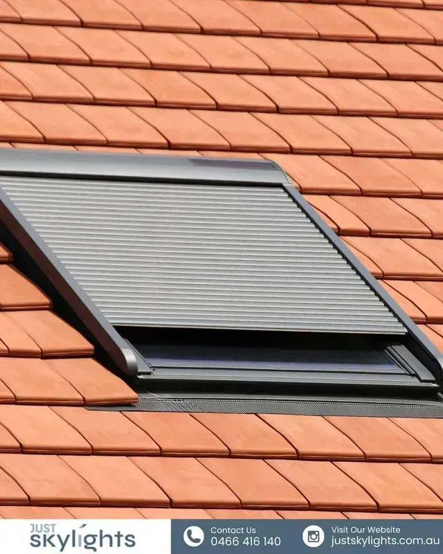 Closed skylight with gray blinds on a terracotta tiled roof