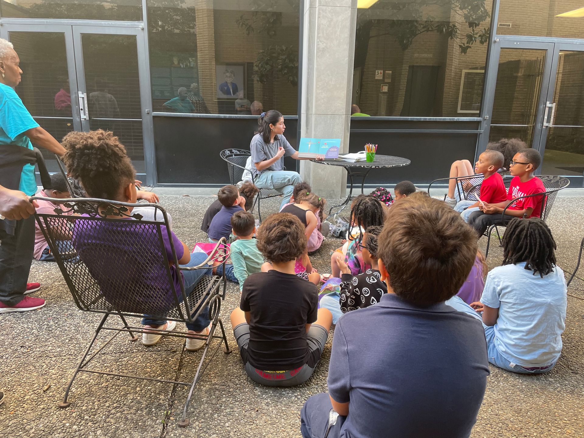 Children's Director reading a gospel storybook to children outside.