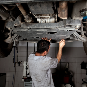 Technician performing repairs under Tesla | Tedious Auto Repair