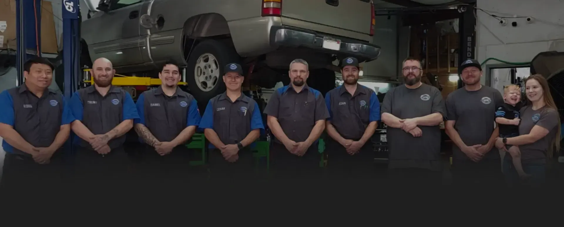 Row of staff in front of truck on lift in our garage | Tedious Auto Repair
