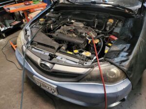 Light blue SUV Subaru with hood up, repairs on AC System in progress | Tedious Auto Repair