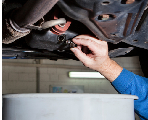 Technician preparing to pour out fluid under vehicle | Tedious Auto Repair