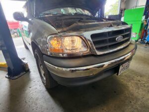 Up close to Ford truck with lights on and hood open | Tedious Auto Repair