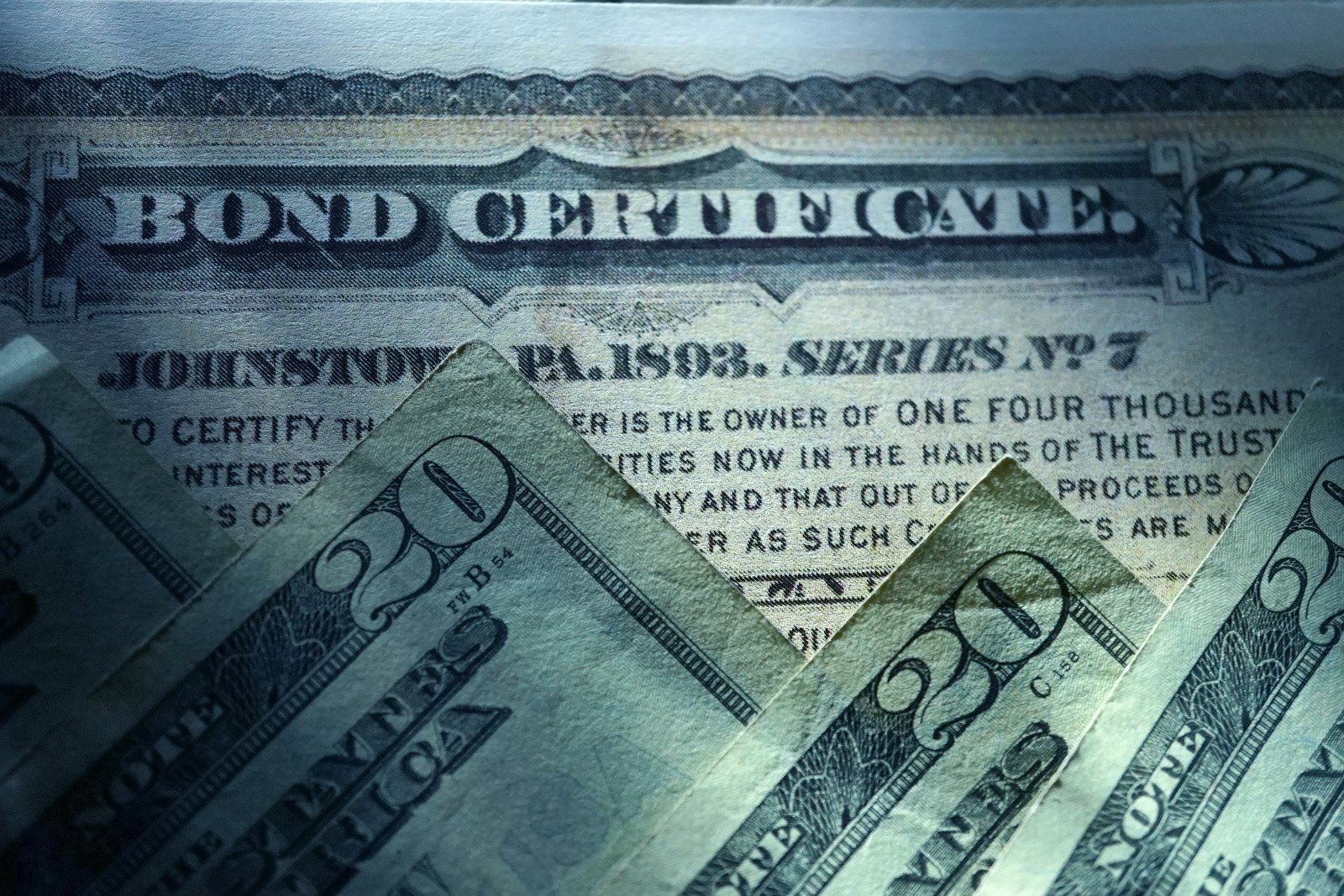 A close up of a bond certificate on top of a 20 dollar bill