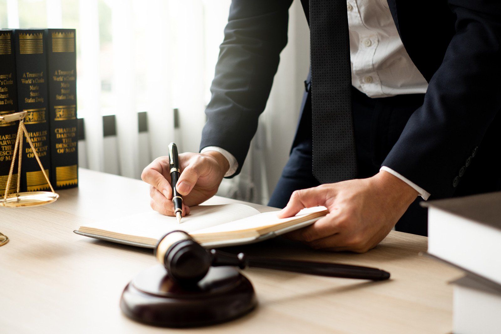 A lawyer is sitting at a desk writing in a notebook.