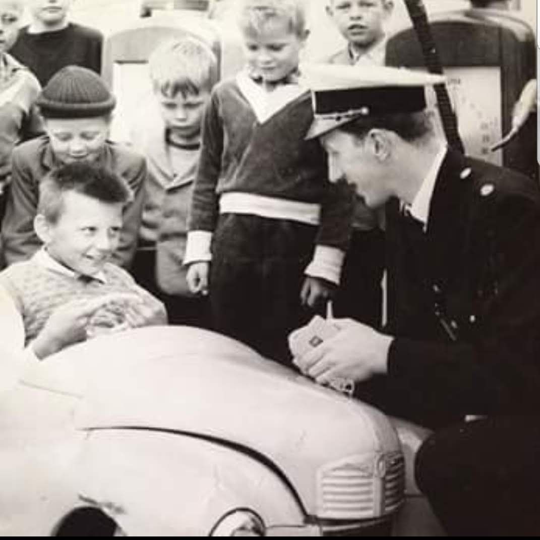 Ett svartvitt foto av en polis talar med en pojke i lådbil