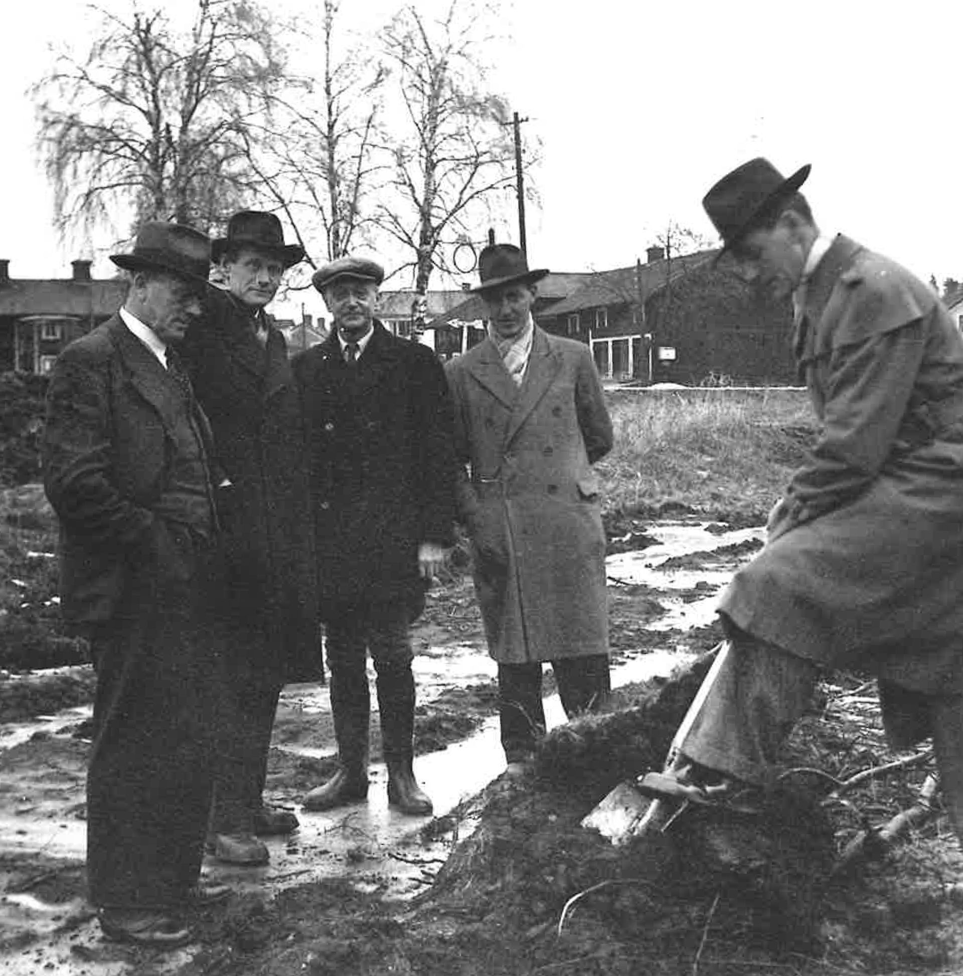 Ett svartvitt foto av en grupp män och en spade