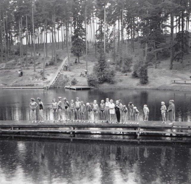 En grupp människor som står på en brygga med utsikt över en sjö