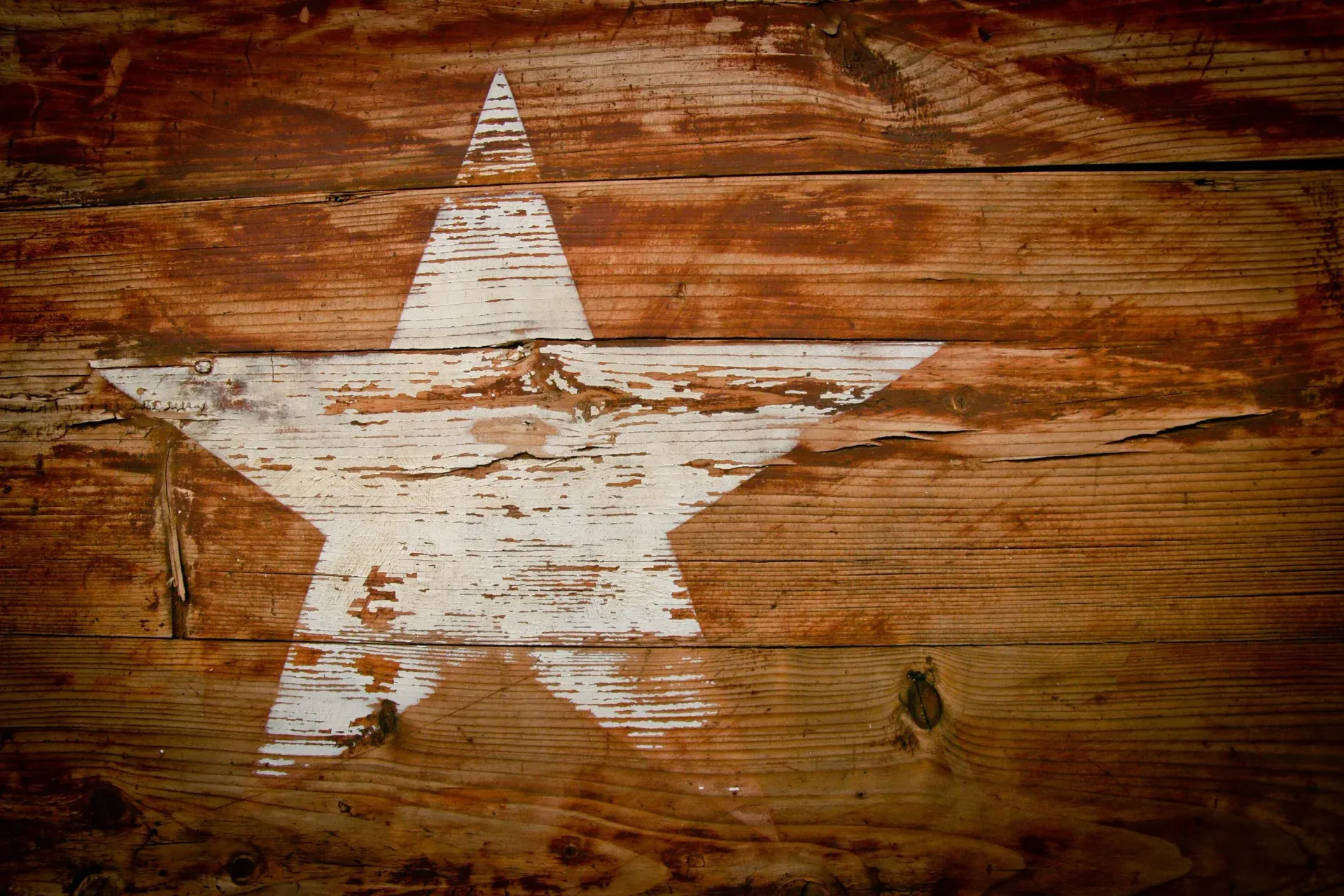 White painted star on weathered brown wooden surface.