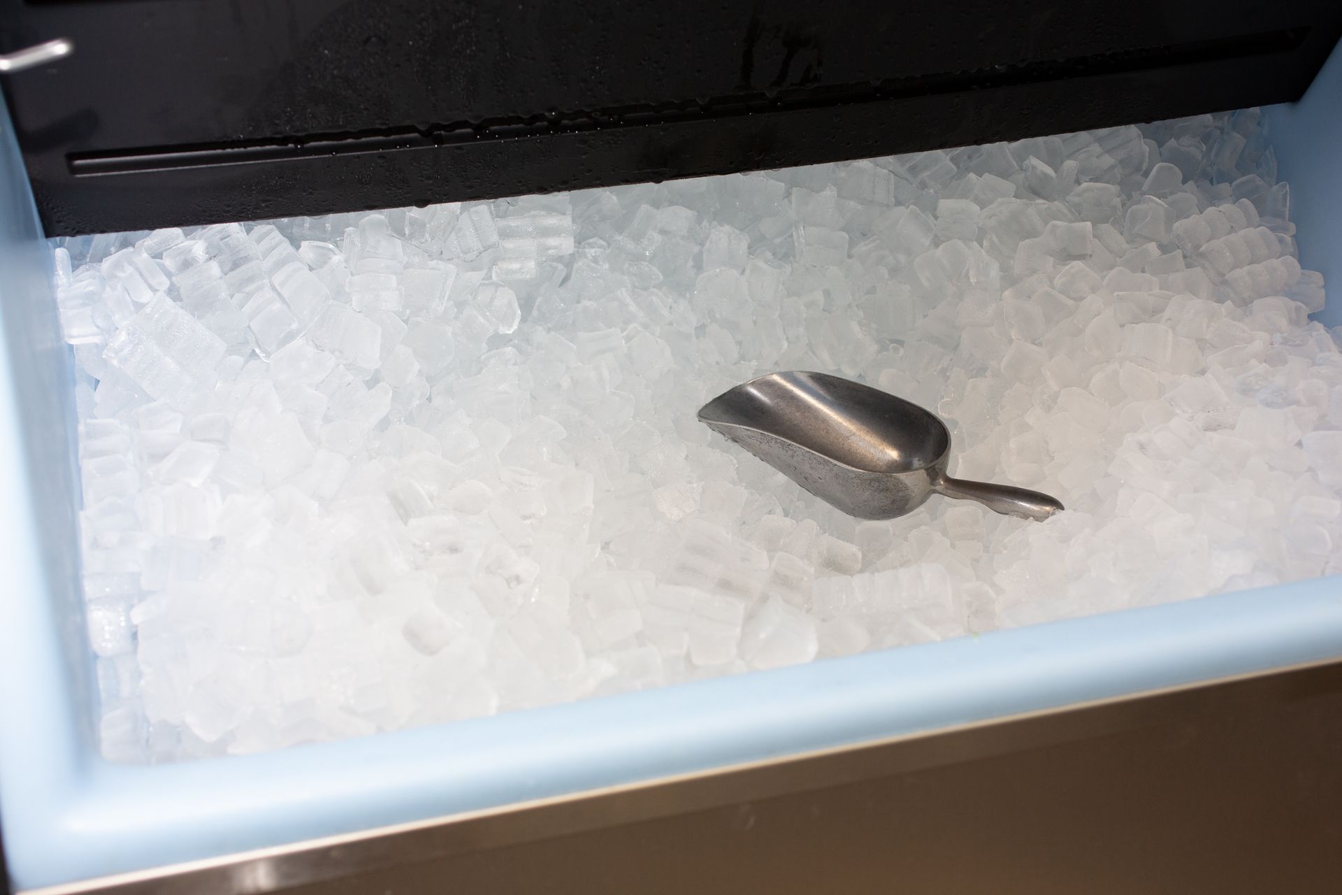 Metal scoop nestled in a fully stocked ice machine, surrounded by fresh ice. Metal scoop nestled in a fully stocked ice machine, surrounded by fresh ice.