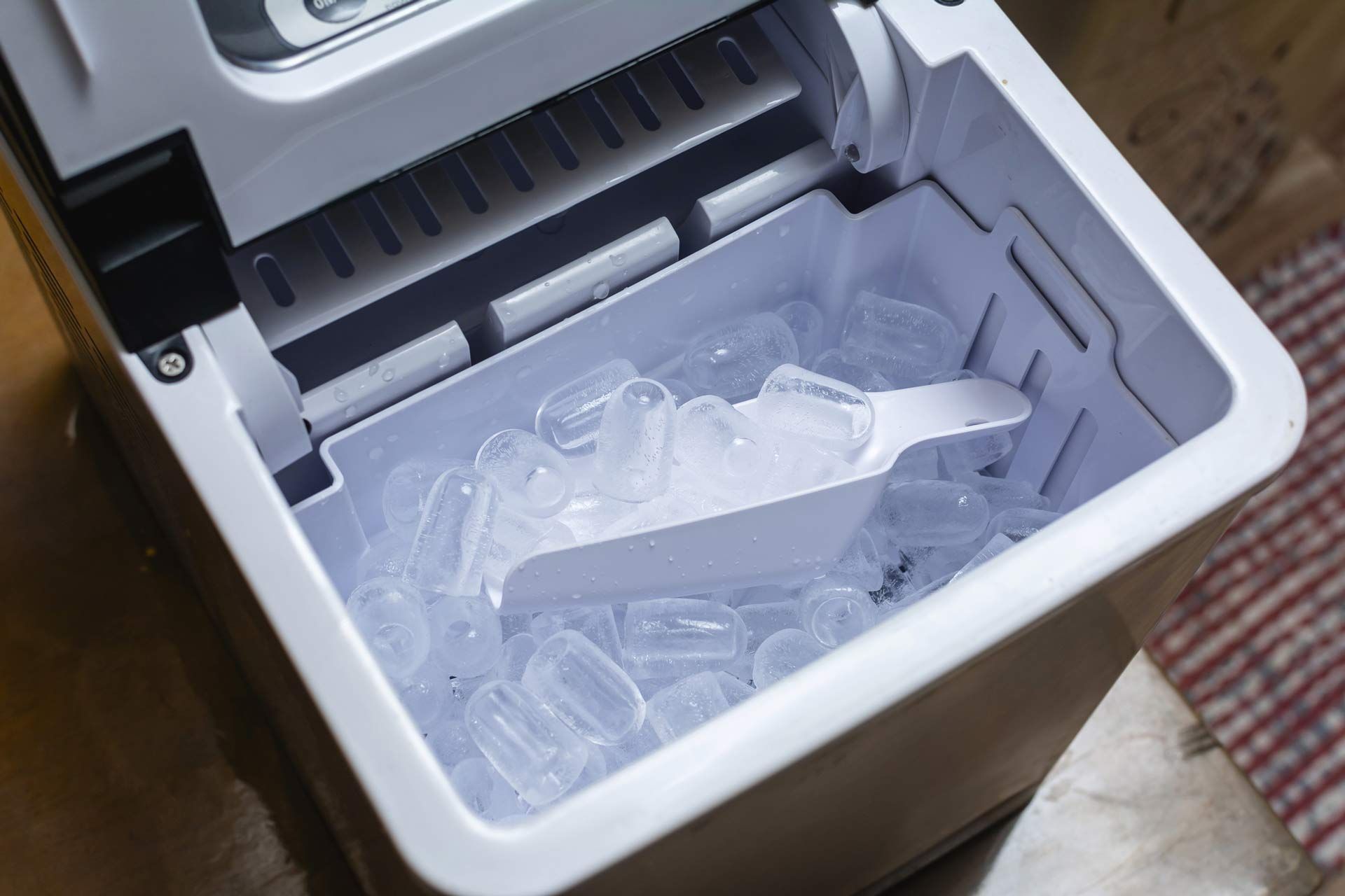Open portable ice maker full of ice cubes with scoop, ideal for ice maker repair services content — Berkeley, CA — Cooper & Hawkins Engineering