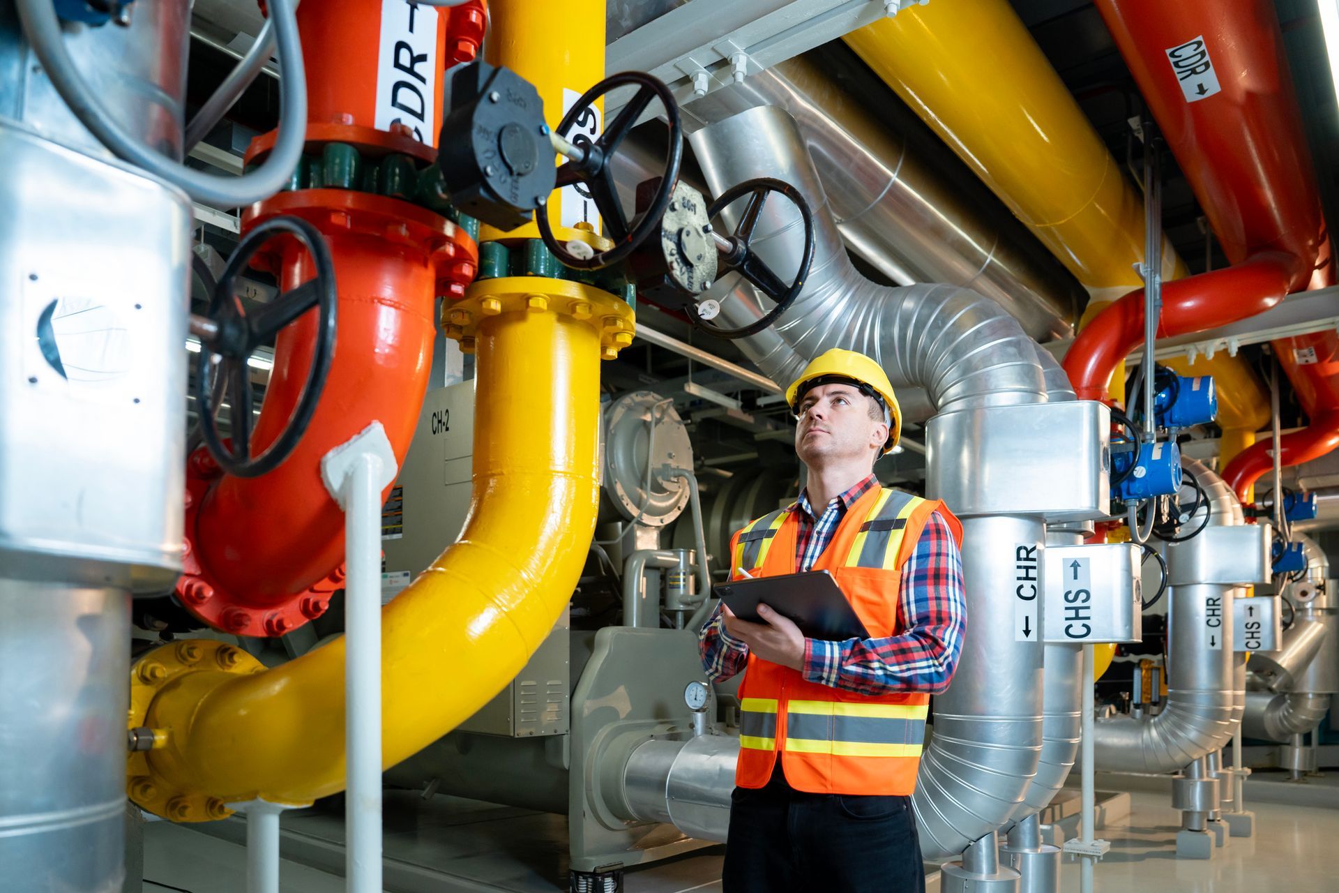 Smart professional engineer using touch pad while standing in boiler control room. Smart professional engineer using touch pad while standing in boiler control room.