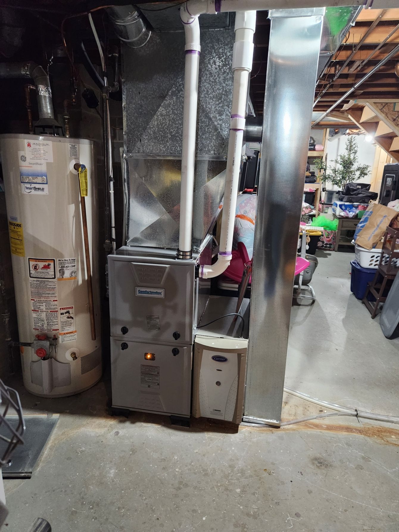 Furnace and water heater in a basement setting. Metal ductwork and pipes are visible.