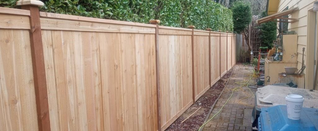 A wooden fence surrounds a lush green yard with trees in the background. A wooden fence surrounds a lush green yard with trees in the background.