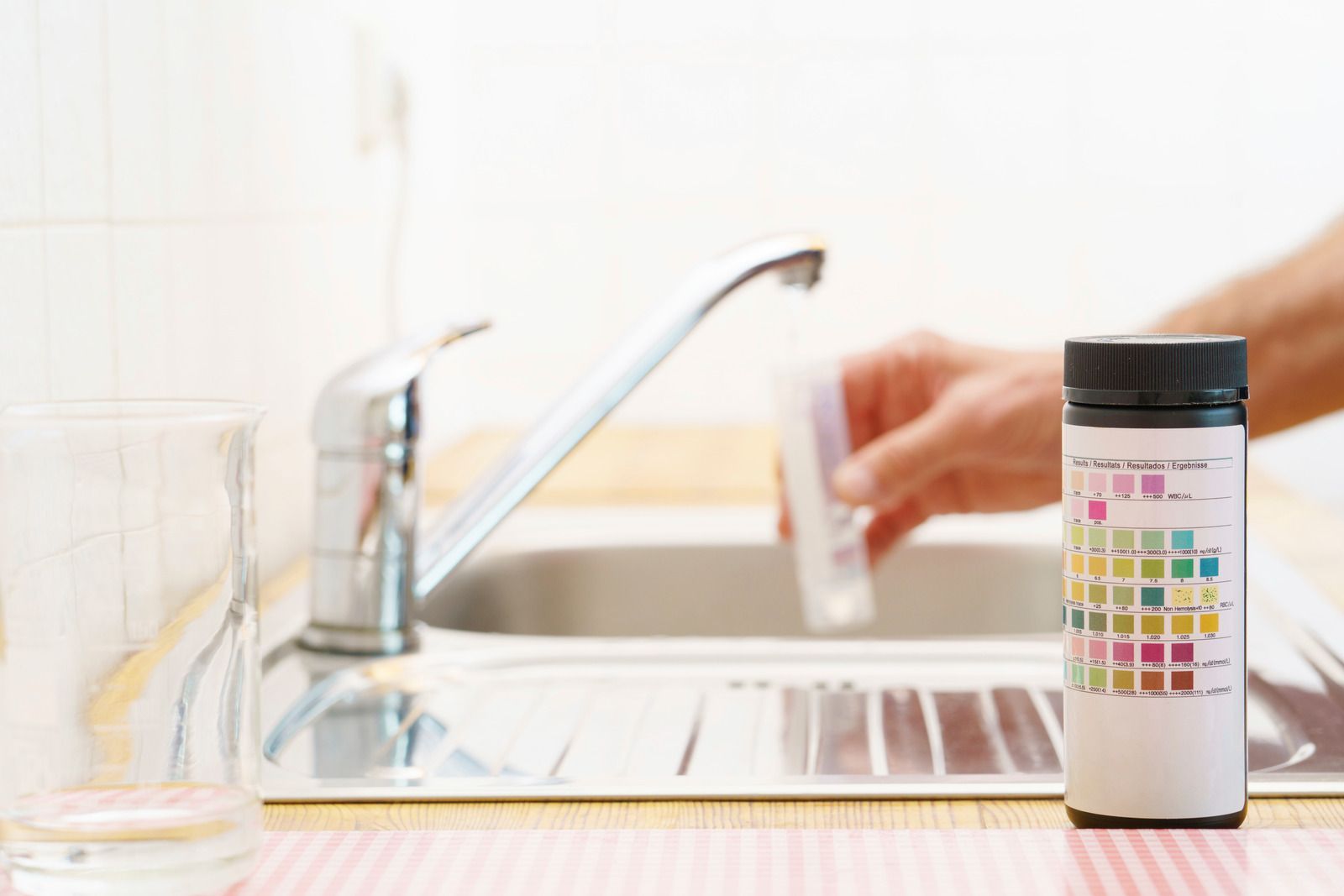 A person is taking a sample of water from a sink.