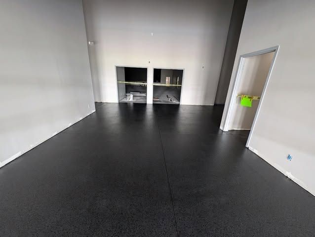 Empty room with black flooring, white walls, and a doorway on the right.