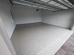 Empty garage with speckled concrete floor and open overhead door