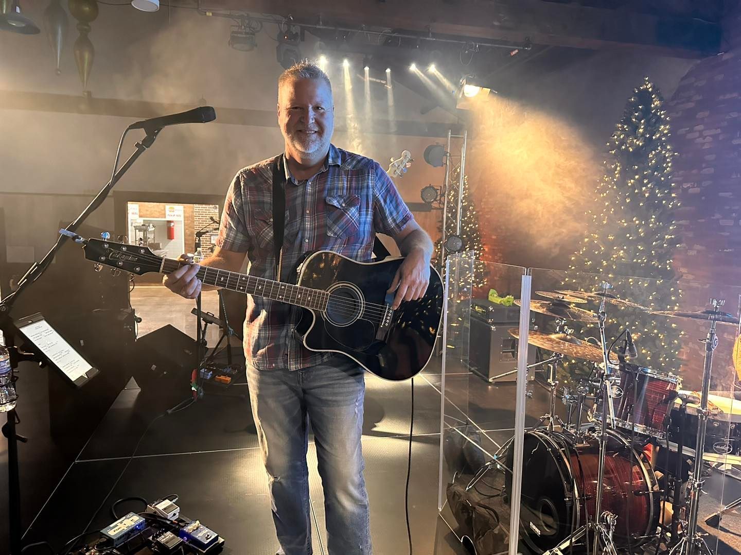 Chris Meldrum is playing a guitar on a stage in front of a microphone.