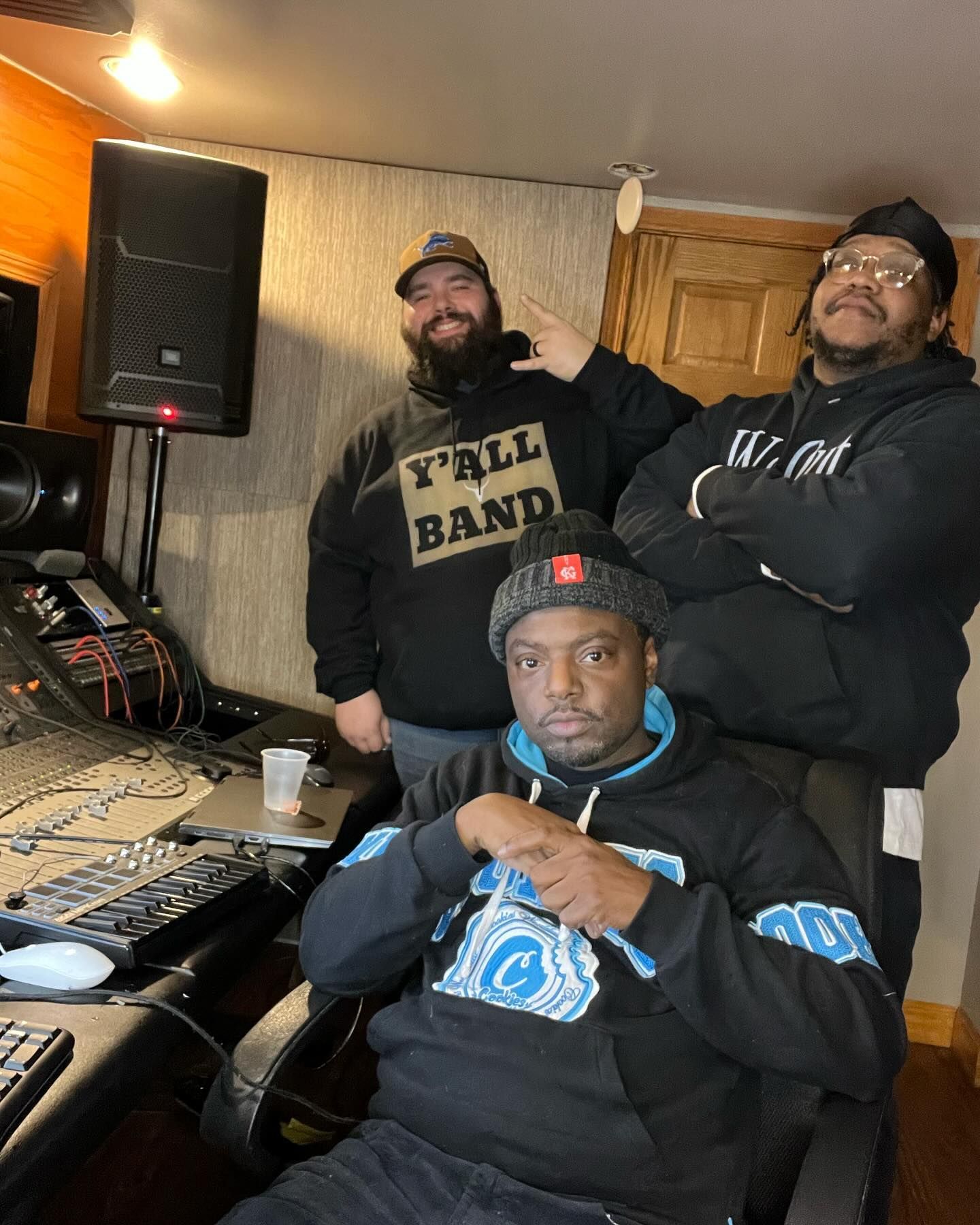 Three men are posing for a picture in a recording studio.