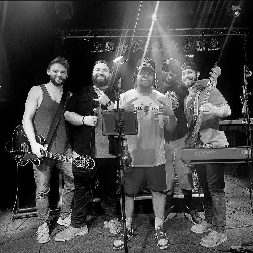 A black and white photo of a group of men standing next to each other on a stage.