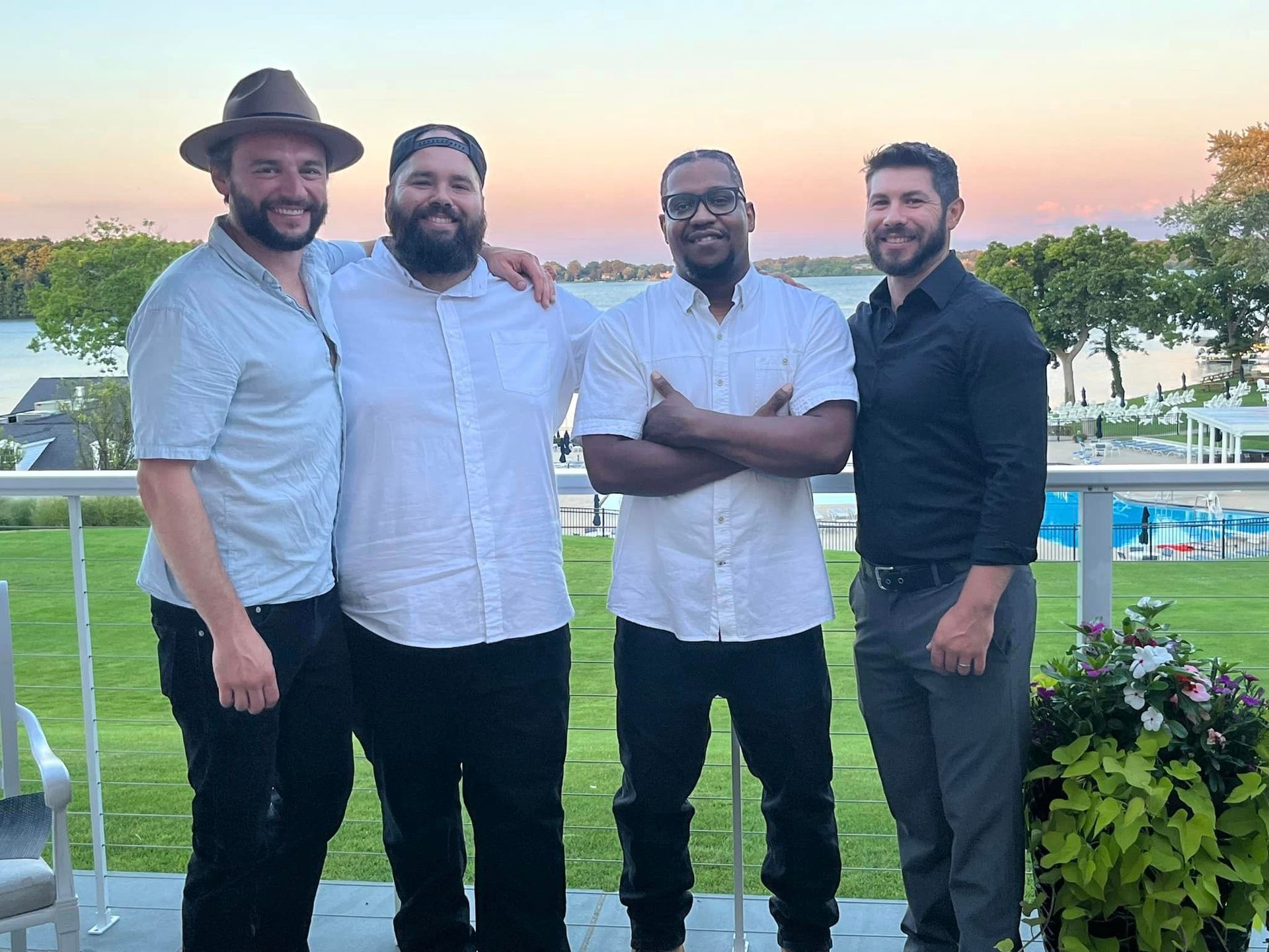 A group of four men standing next to each other on a balcony.
