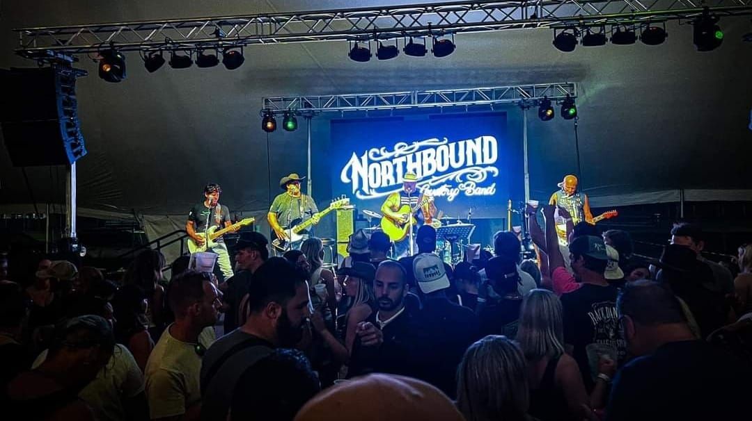 A group of people are standing in front of a stage at a concert.