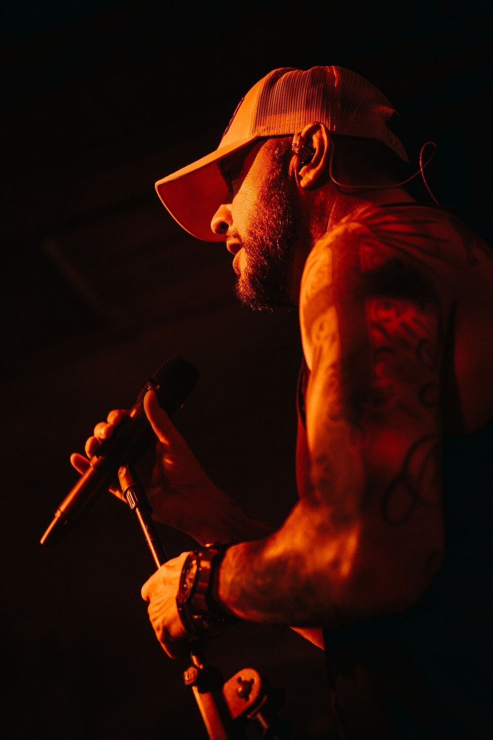 A man is singing into a microphone in a dark room.