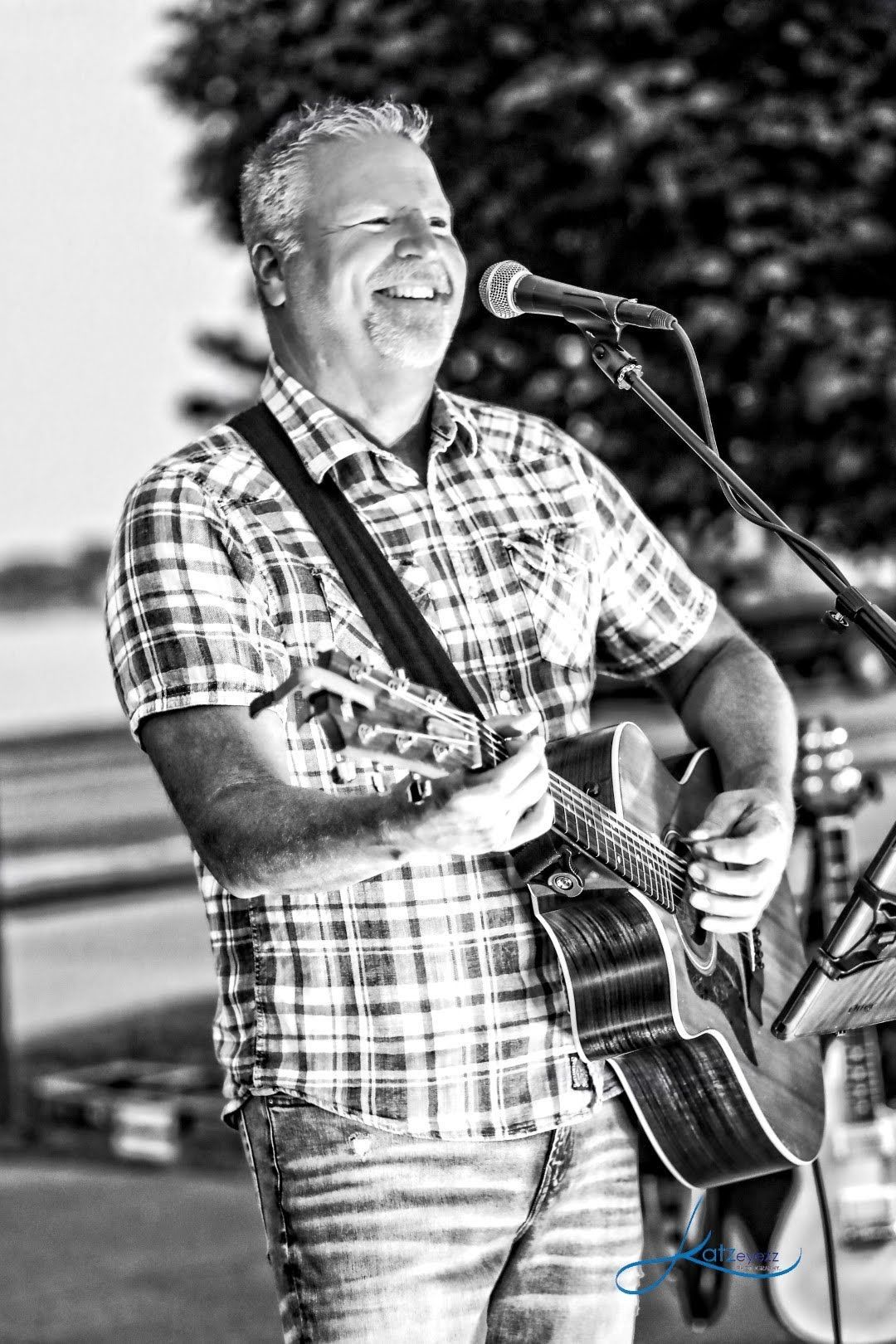 Chris meldrum is playing a guitar and singing into a microphone in a black and white photo.