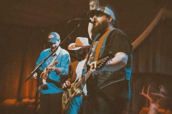 A group of men are playing guitars and singing into microphones on a stage.