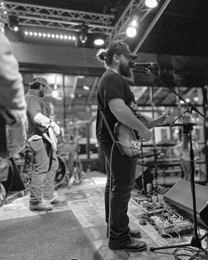 A man is playing a guitar and singing into a microphone on a stage.