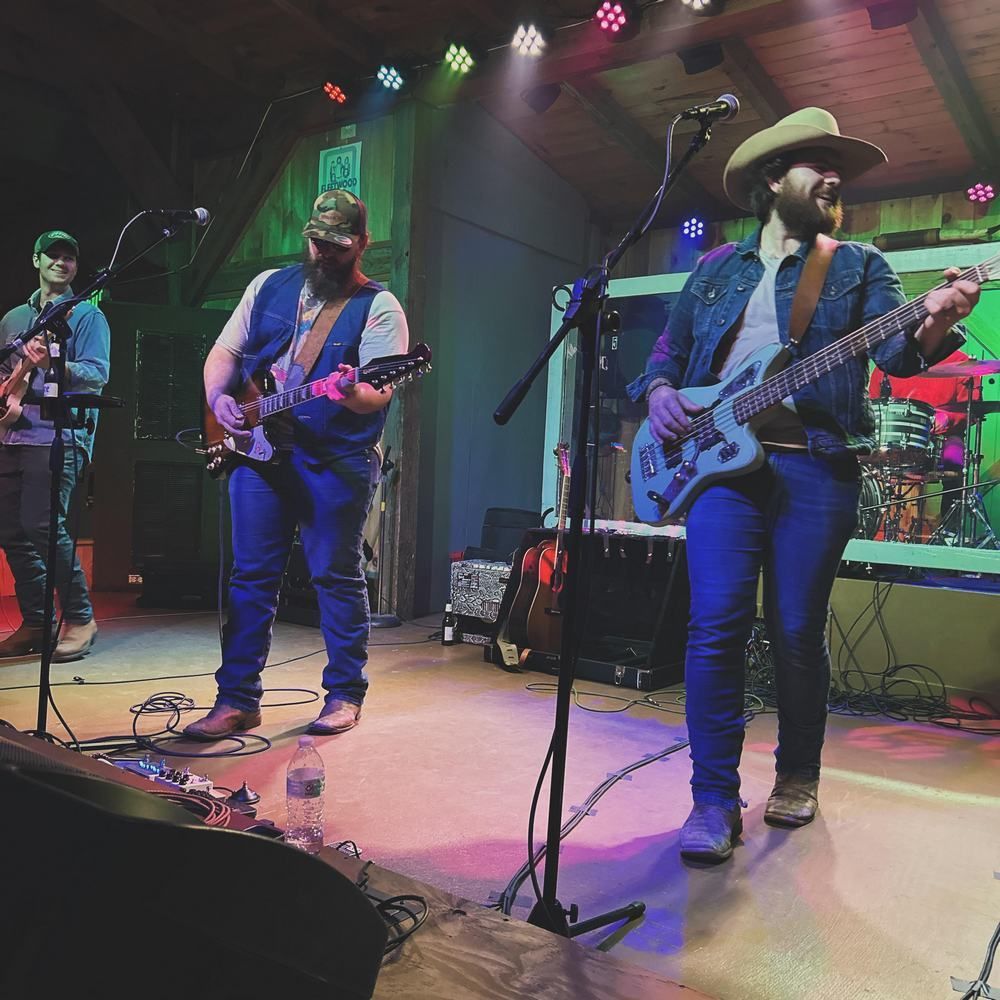 A man in a cowboy hat is playing a guitar on stage.