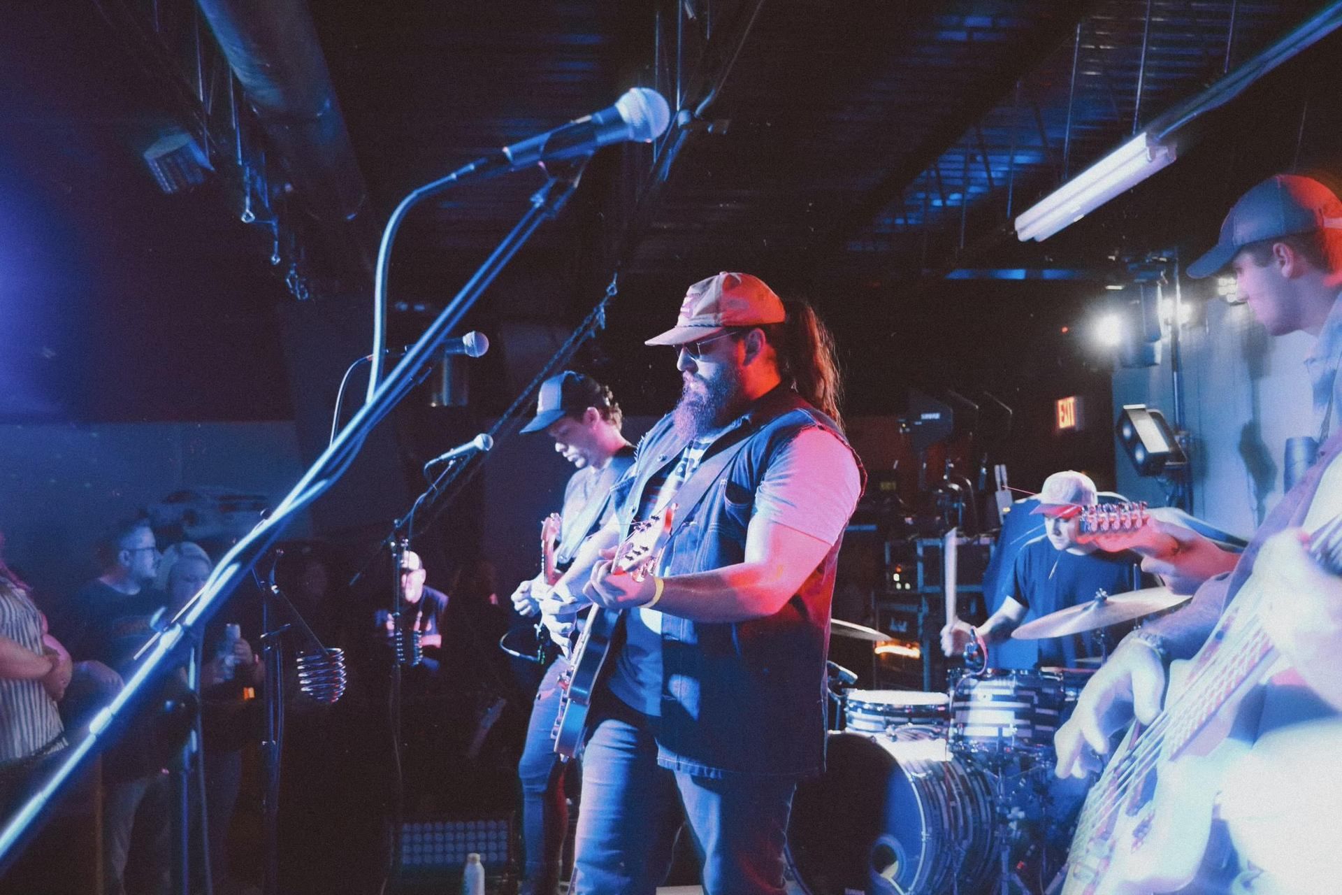 A man is singing into a microphone while playing a guitar on stage.