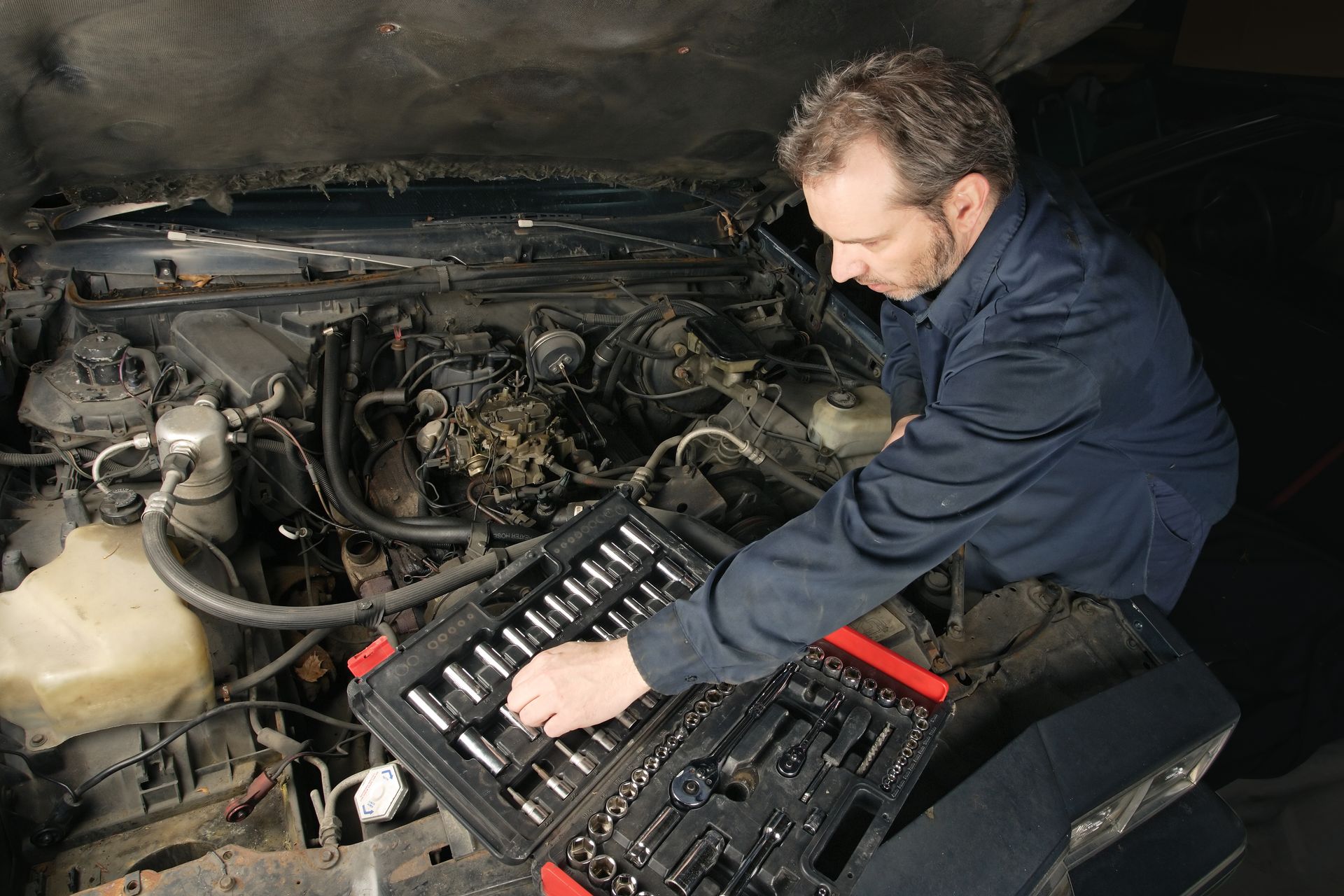 A man is working on the engine of a car.