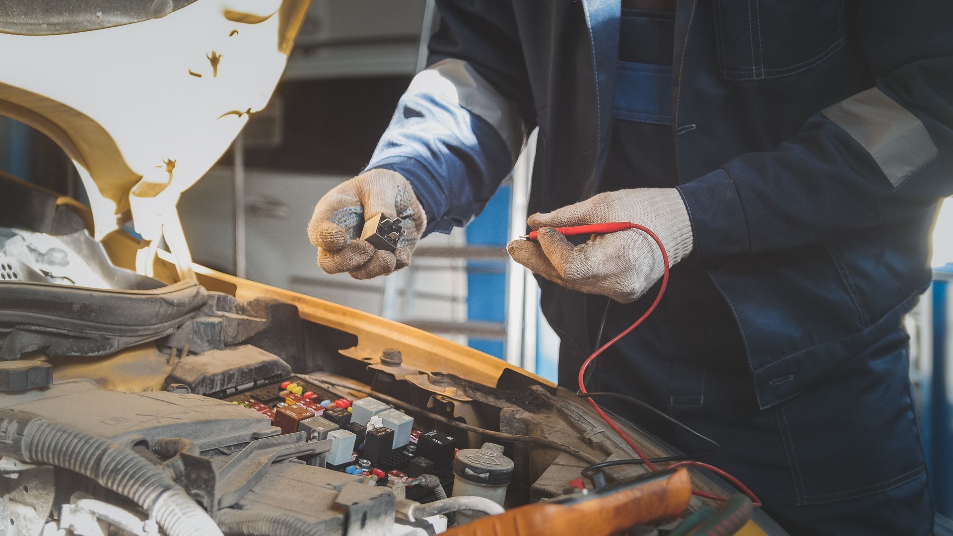 A man is working on a car with a voltmeter.