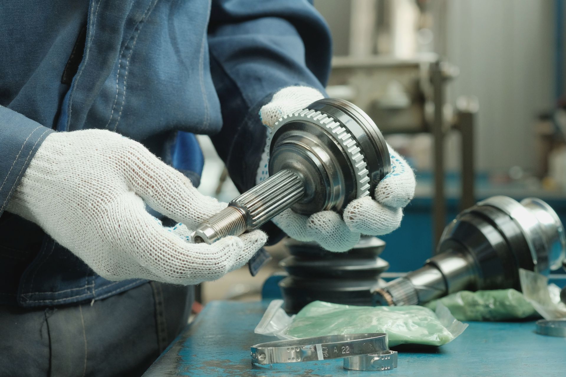 A mechanic is working on a cv joint in a garage.