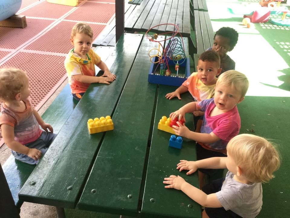 A Group of Children Are Sitting at a Picnic Table Playing With Toys