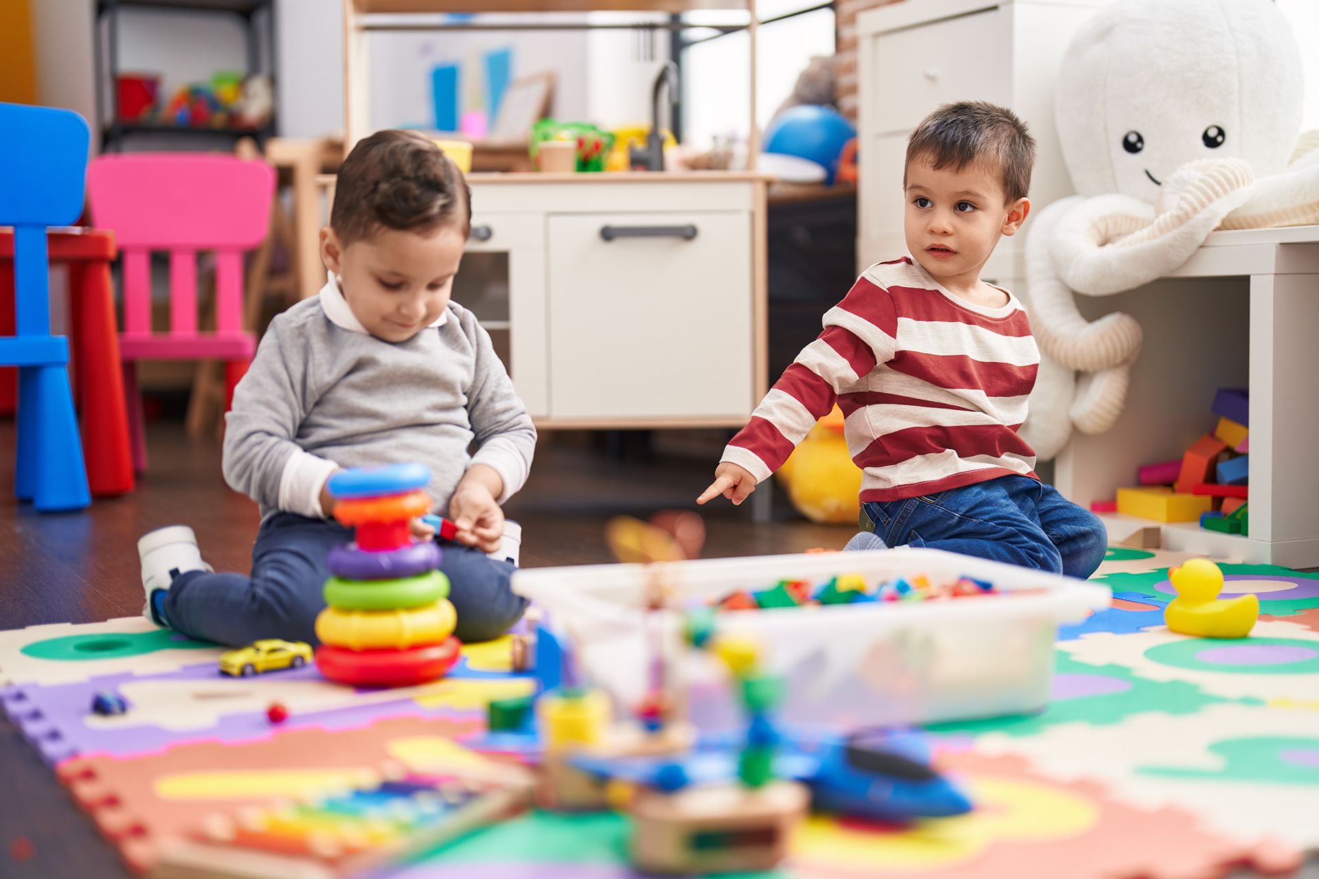 Two Young Boys Are Sitting on the Floor Playing With Toys