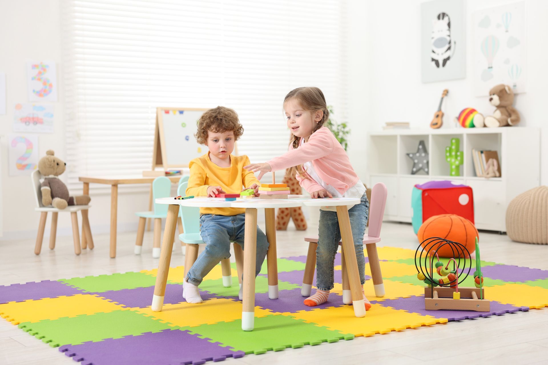 Boy and a Girl Are Playing With Toys at a Table in a Playroom
