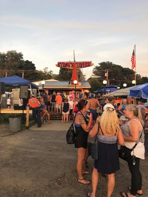 A group of people standing in front of a sign that says stowe 's tavern